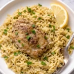 One pot lemon chicken orzo served with a seared chicken thigh, fluffy lemon orzo, fresh parsley, and a lemon wedge