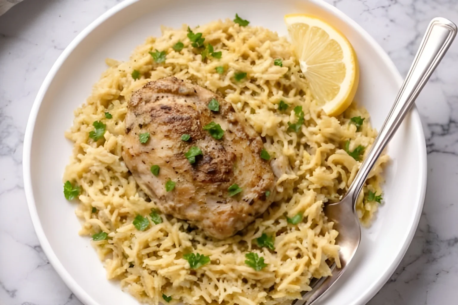 One pot lemon chicken orzo served with a seared chicken thigh, fluffy lemon orzo, fresh parsley, and a lemon wedge
