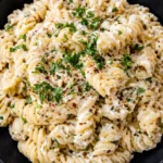 Creamy cottage cheese pasta made with rotini, garlic parmesan sauce, fresh herbs, and cracked black pepper served in a black bowl