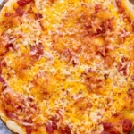 Greek yogurt pizza dough baked into a thin crust pizza topped with melted cheese and tomato sauce on a wooden board