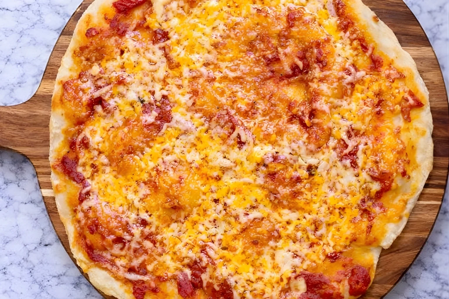 Greek yogurt pizza dough baked into a thin crust pizza topped with melted cheese and tomato sauce on a wooden board