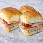 Italian pesto sandwiches made with ham salami pepperoni provolone cheese and sun dried tomatoes on soft baked rolls