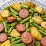 Smoked sausage and potatoes with green beans on white plate