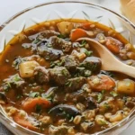Bowl of Slow Cooker Beef Barley Stew filled with tender beef, carrots, mushrooms, and potatoes in a thick savory broth, garnished with fresh parsley and served with crusty bread.