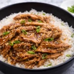 Crockpot teriyaki chicken served over white rice with sesame seeds and green onions