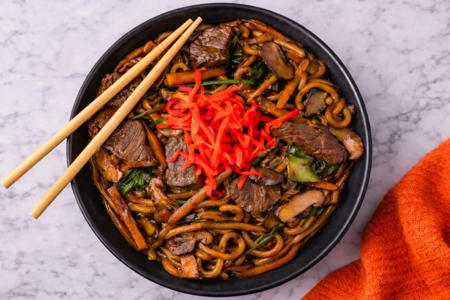 Beef yaki udon noodles with tender steak, vegetables, and savory sauce in a black bowl