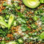 Mexican spaghetti with ground beef, jalapenos, avocado, cilantro, and cotija cheese in a skillet