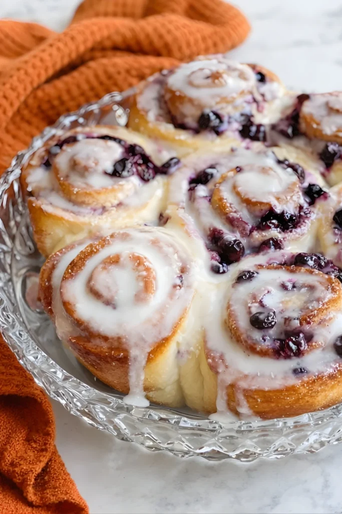 Close-up of blueberry lemon sourdough sweet rolls with lemon glaze in a glass dish, served warm and golden brown