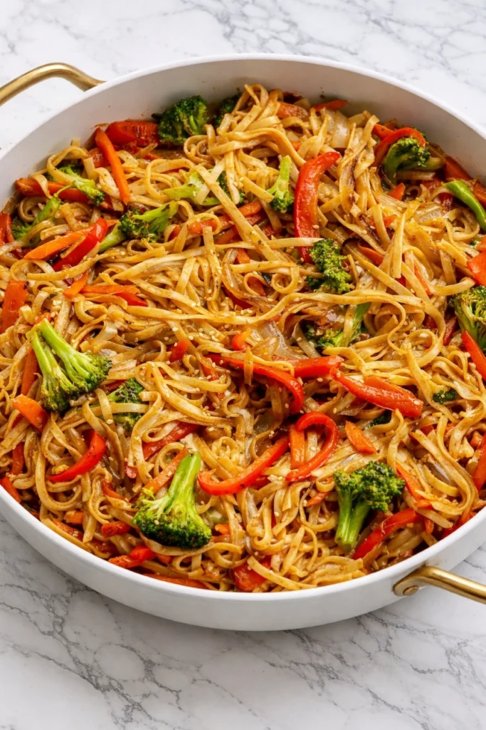 Veggie Lo Mein noodles stir-fried with broccoli, red bell peppers, and carrots in a white skillet