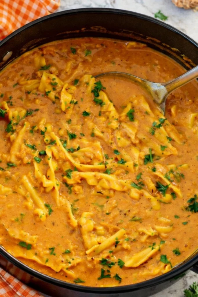 Creamy vegan lasagna soup in a pot with broken noodles and parsley