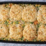 Chicken pot pie casserole topped with golden cheesy biscuits in a baking dish