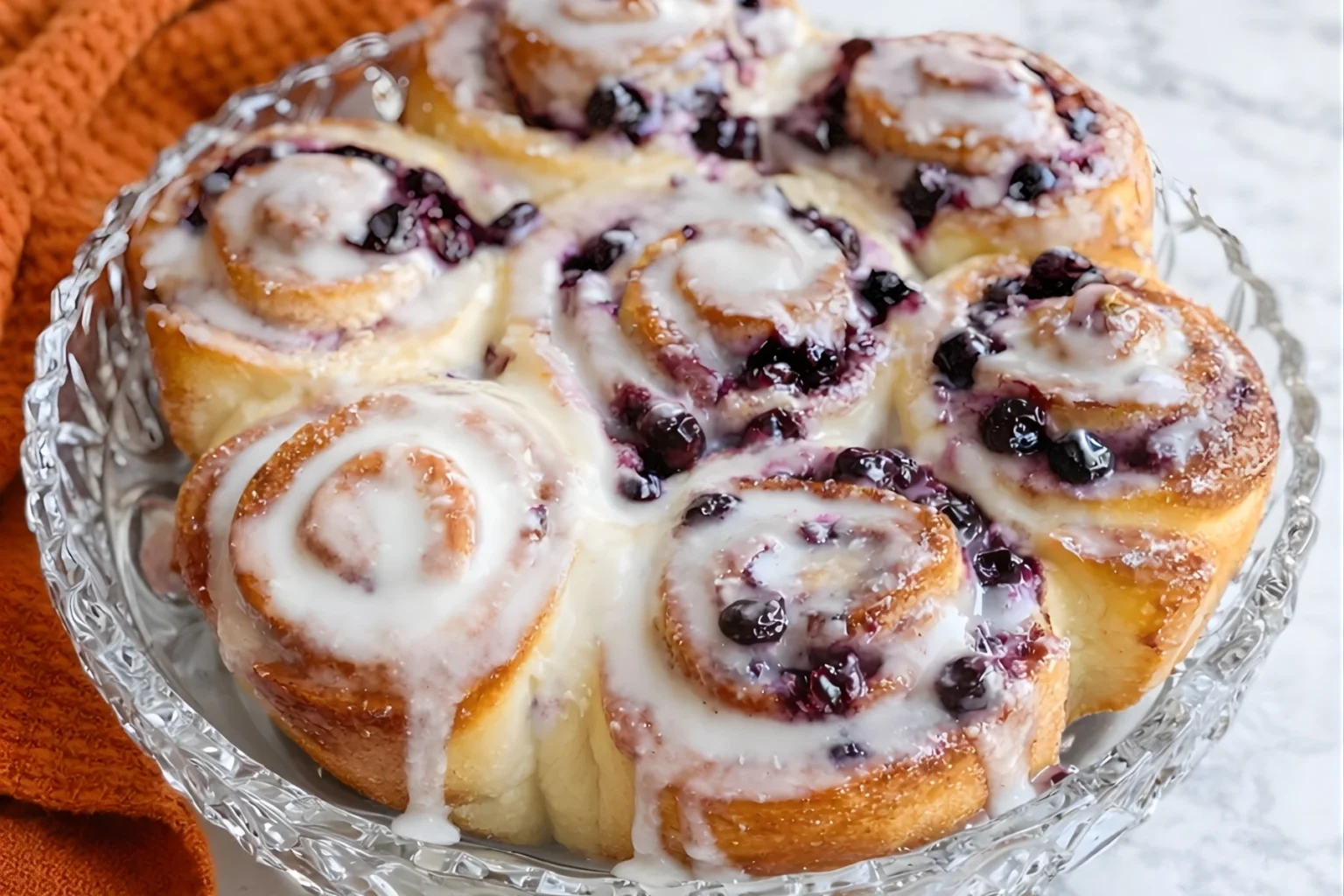 Blueberry lemon sourdough sweet rolls topped with lemon glaze and baked until soft and golden in a glass dish