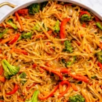 Veggie Lo Mein noodles with broccoli, bell peppers, and carrots in a white skillet