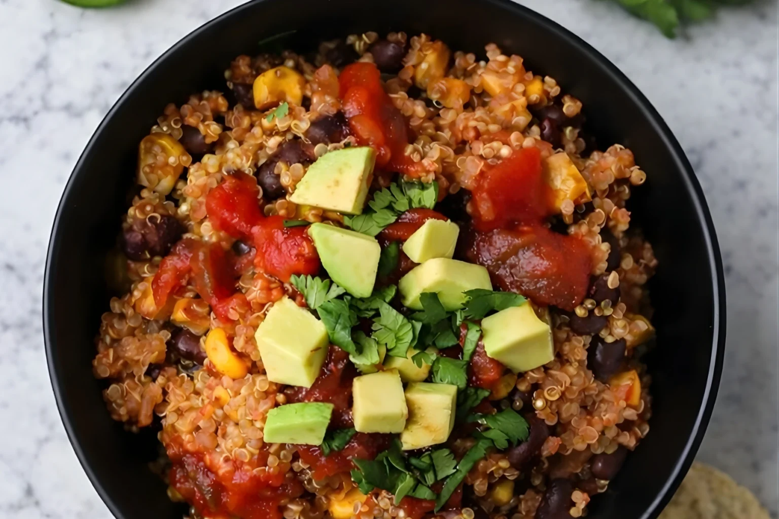 Instant Pot Mexican Quinoa topped with avocado, black beans, corn, salsa, and fresh cilantro in a black bowl