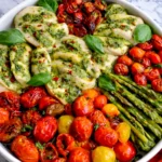 One pan pesto chicken with roasted cherry tomatoes and asparagus in a white dish