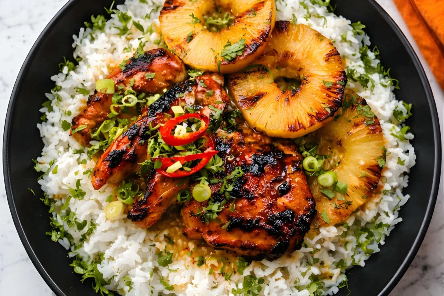 Grilled Hawaiian chicken with caramelized pineapple rings over coconut rice, garnished with fresh herbs and sliced red chili