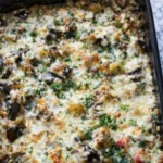 Baked eggplant casserole with melted cheese herbs and vegetables in a casserole dish