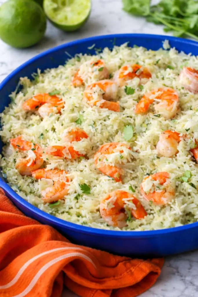 Close up of Cilantro Lime Shrimp & Rice in a blue skillet with fluffy herb rice, tender shrimp, fresh cilantro, and sliced limes