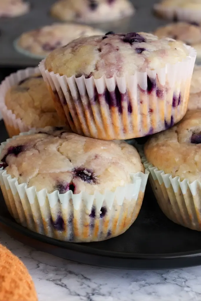Close up of sourdough discard blueberry lemon muffins showing purple streaks and fluffy texture