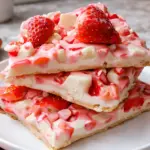Yogurt strawberry bark bites with fresh strawberries and white chocolate on a plate