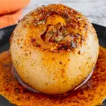 Viral onion boil recipe with caramelized layers, cajun seasoning, and melted butter on black plate