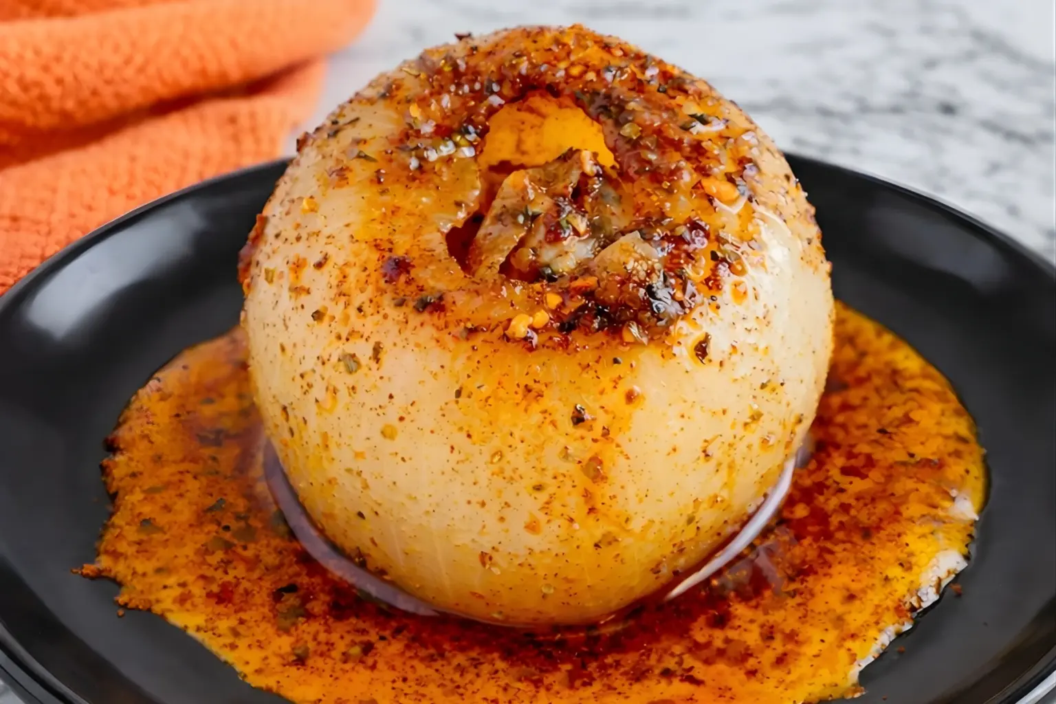 Viral onion boil recipe with caramelized layers, cajun seasoning, and melted butter on black plate