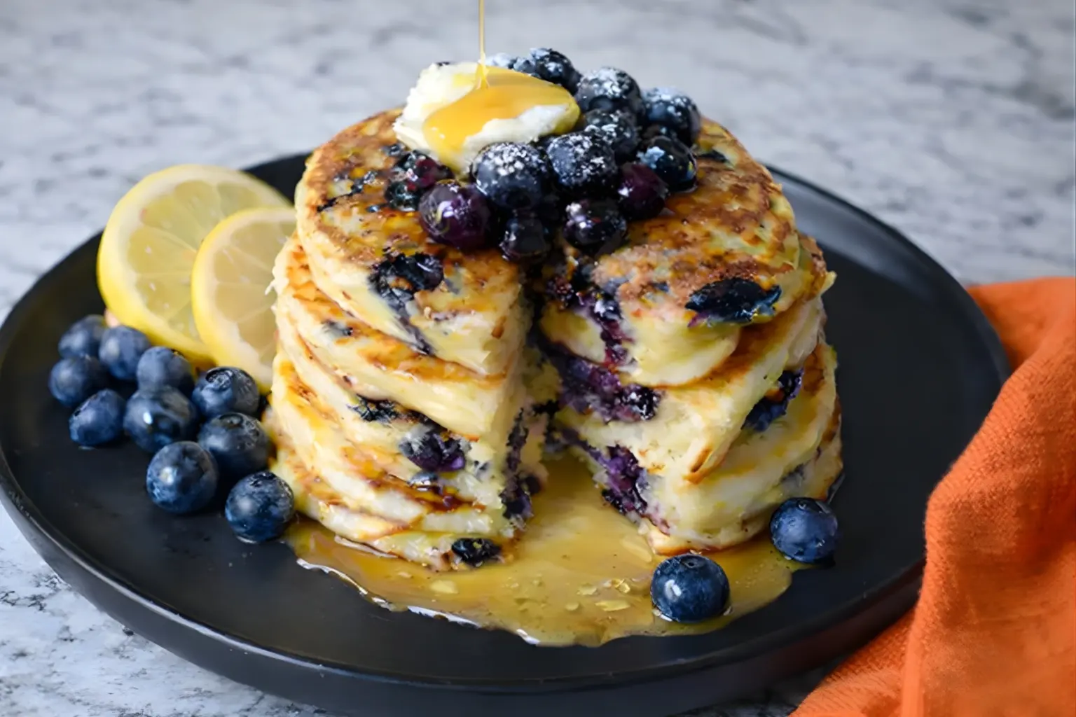 Stack of lemon blueberry sourdough pancakes with syrup and butter