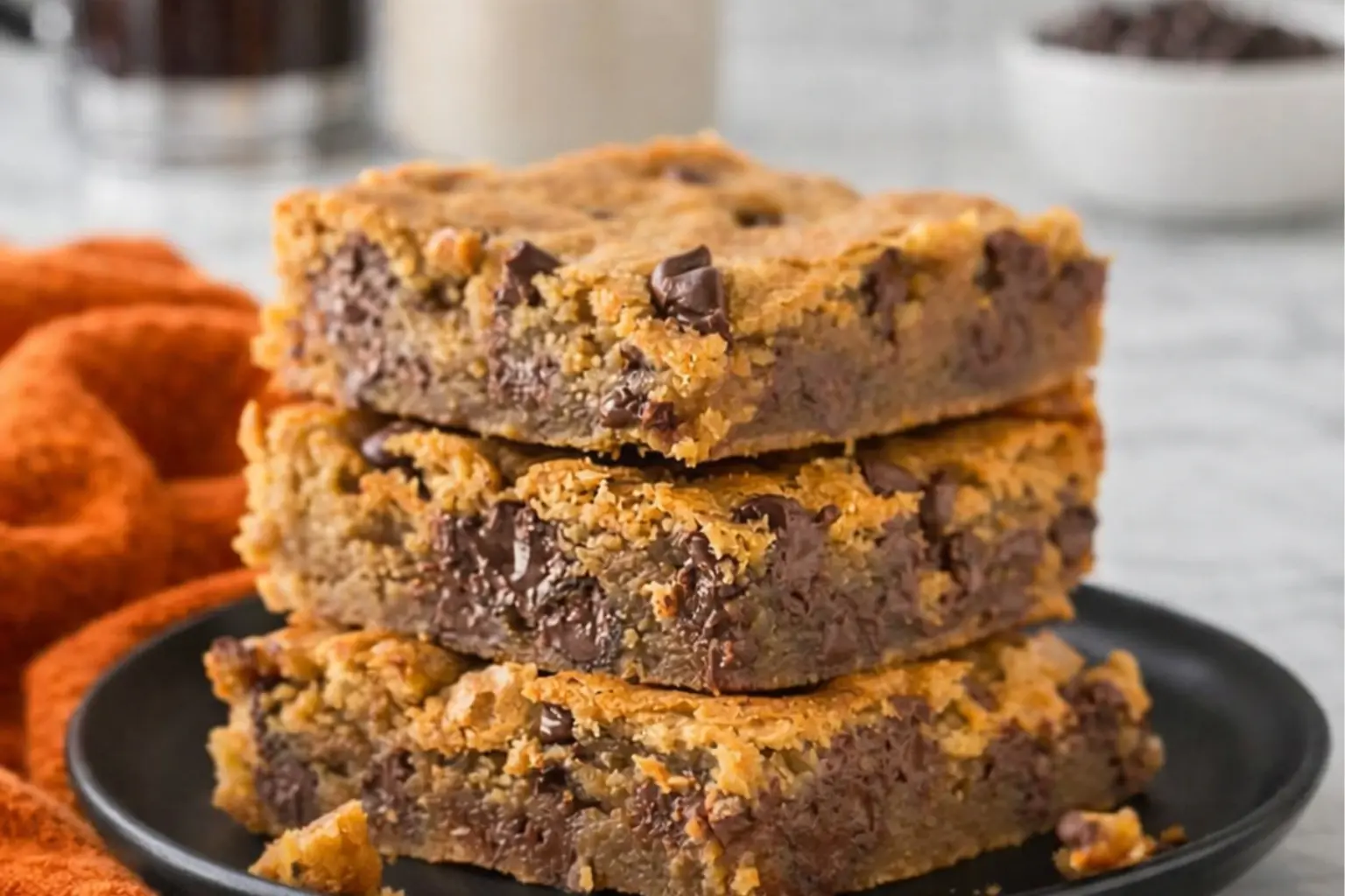 Peanut Butter Chocolate Chip Bars stacked on a plate showing soft chewy texture with melted chocolate chips