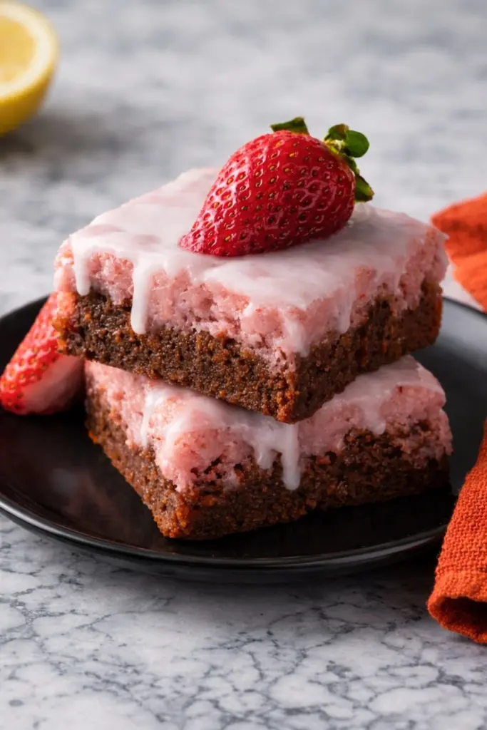 Strawberry brownies with pink icing on black plate