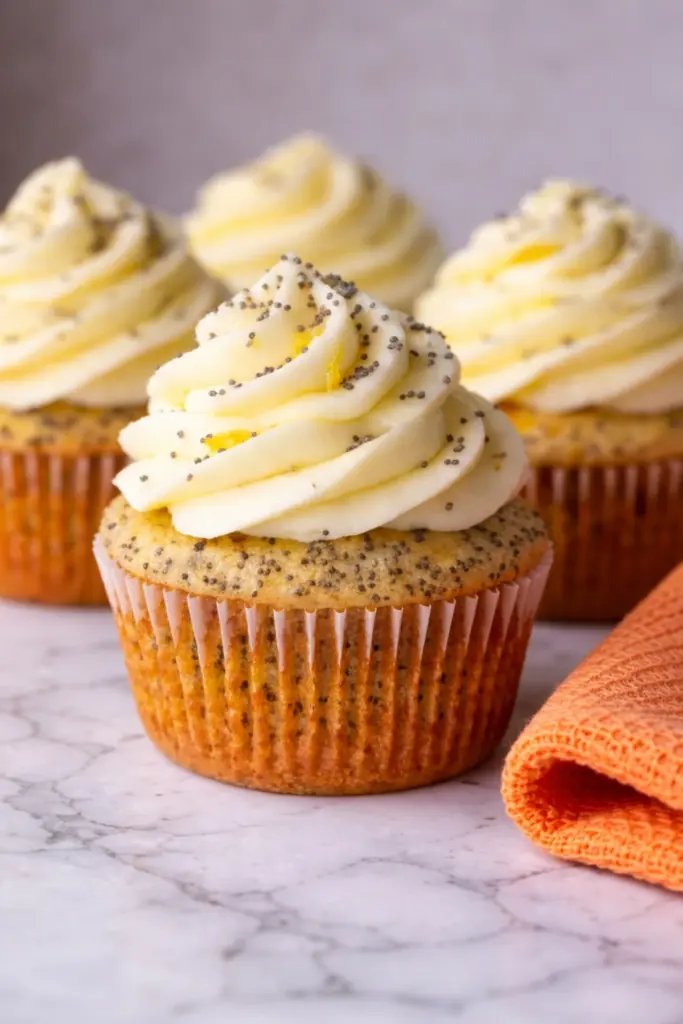Close up lemon poppy seed cupcake with creamy lemon frosting and poppy seeds