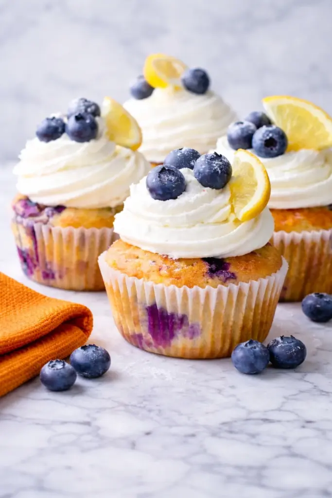 Homemade lemon blueberry cupcakes with creamy frosting and fresh blueberries on marble surface