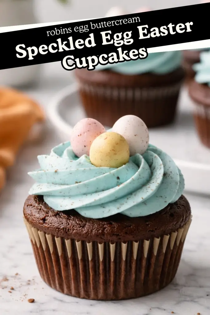Speckled Egg Easter Cupcake with blue buttercream and pastel mini eggs on marble countertop