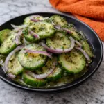 Italian Cucumber Salad in Black Bowl on Marble Countertop