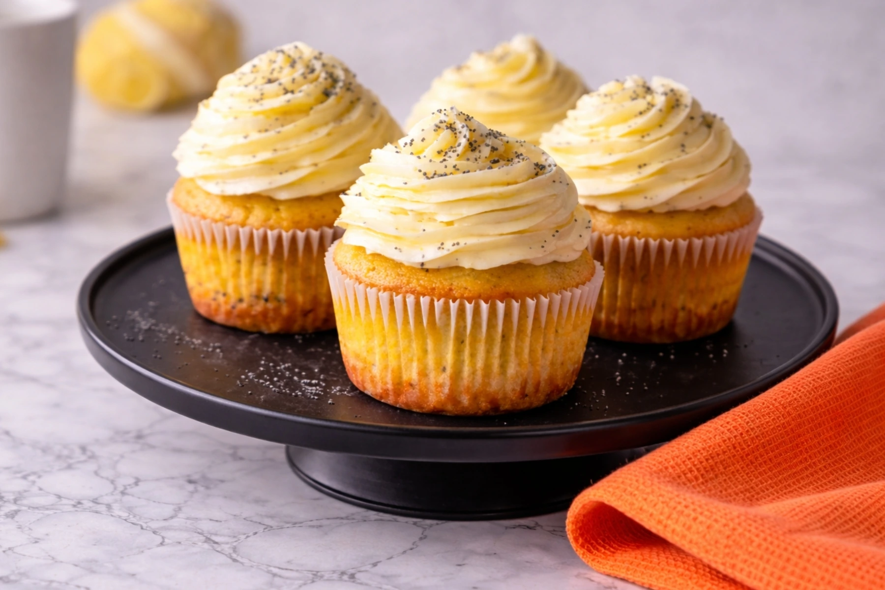 Lemon Poppy Seed Cupcakes with creamy frosting on black plate marble countertop