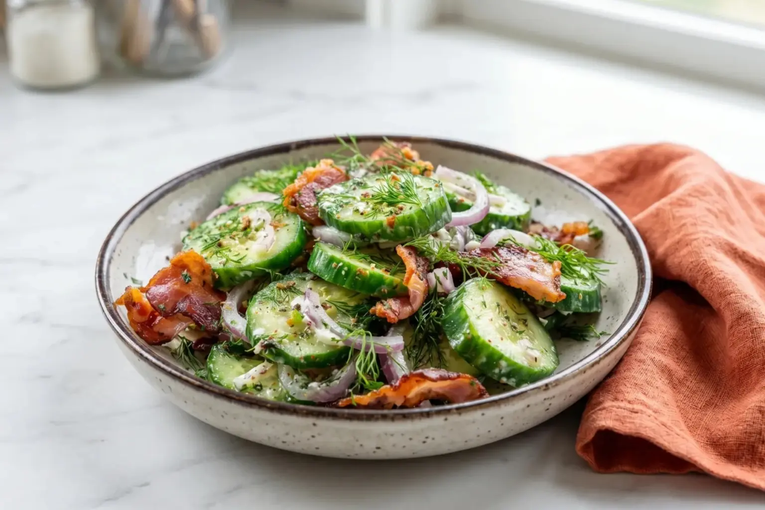 Cucumber salad with crispy bacon and red onion in creamy dill dressing