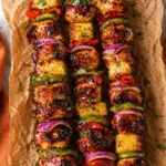 Grilled BBQ Chicken Kabobs with pineapple, peppers, red onion, and glossy BBQ sauce on parchment paper