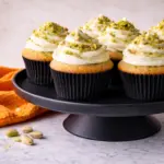 Pistachio cupcakes with creamy frosting on black cake stand