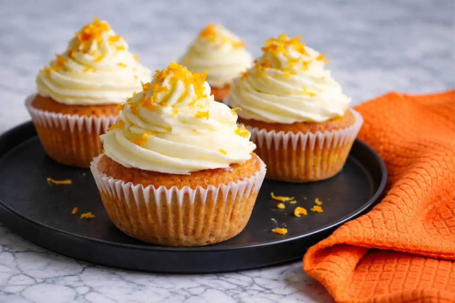 Orange Blossom Cupcakes with Creamy Frosting on Black Plate