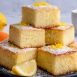 Lemon brownies stacked with powdered sugar and fresh lemon zest