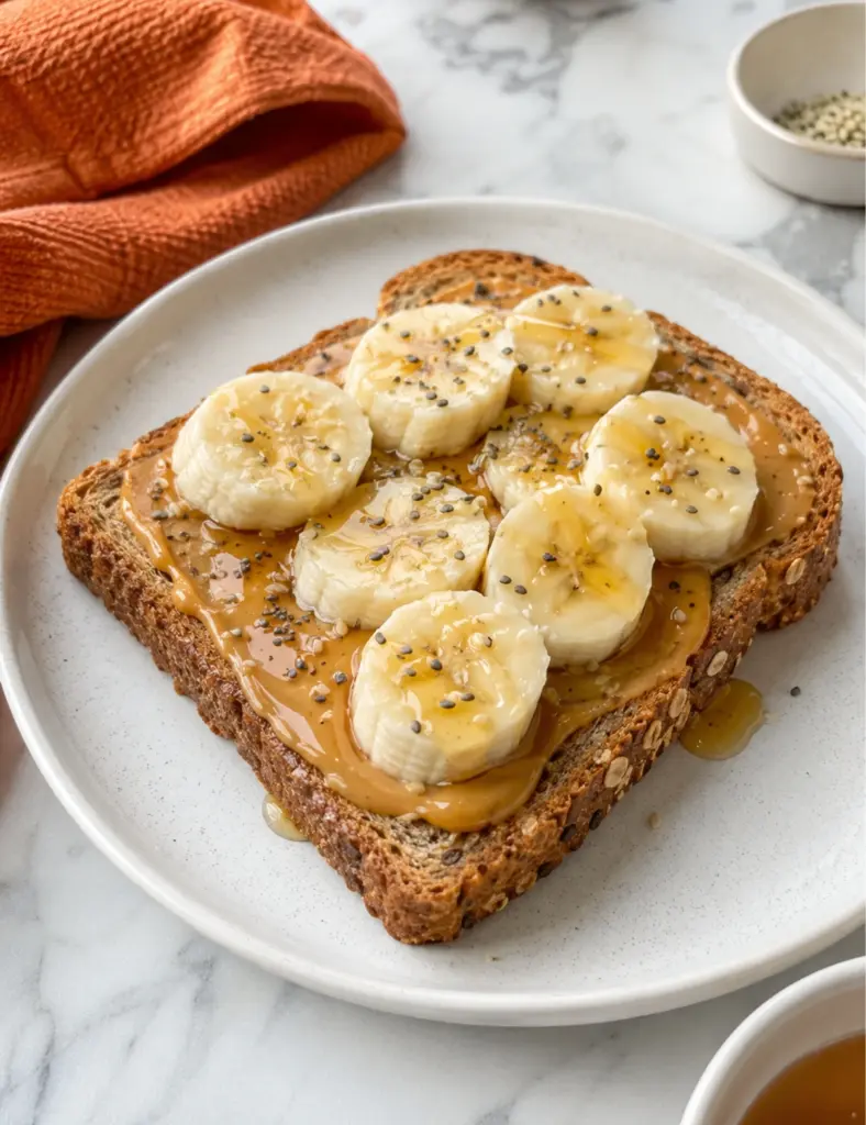 Peanut butter banana toast with honey and seeds on whole grain bread
