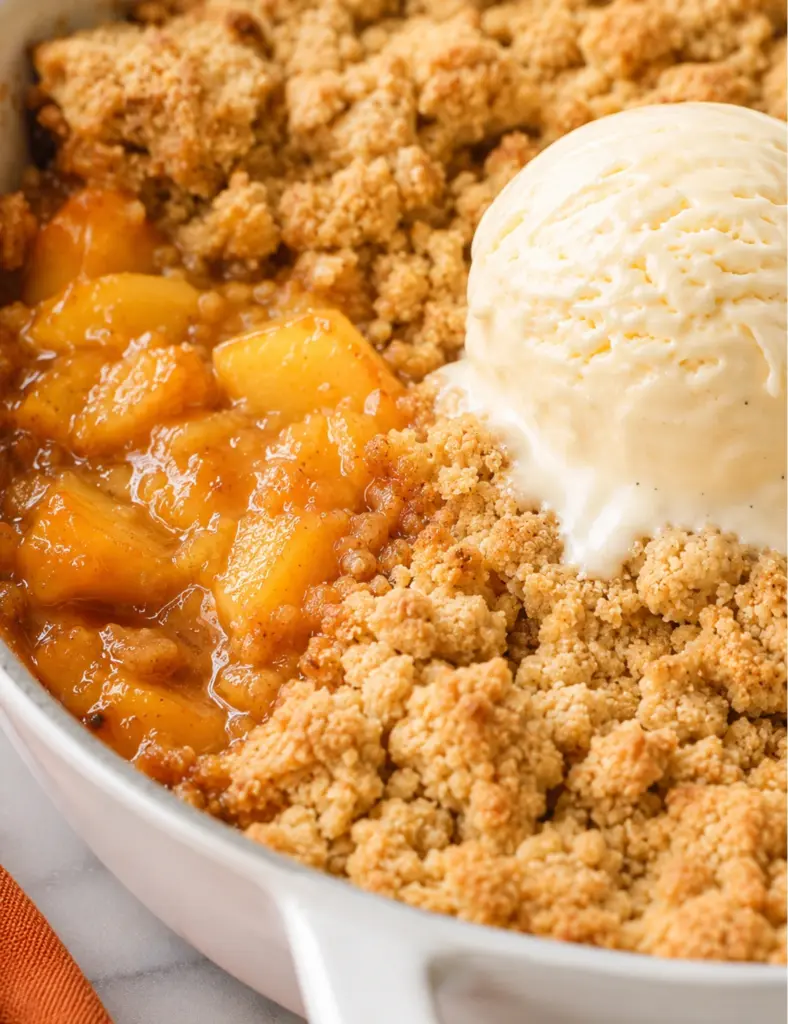 Cast Iron Skillet Peach Cobbler with juicy peach filling, golden crumble topping, and melting vanilla ice cream.