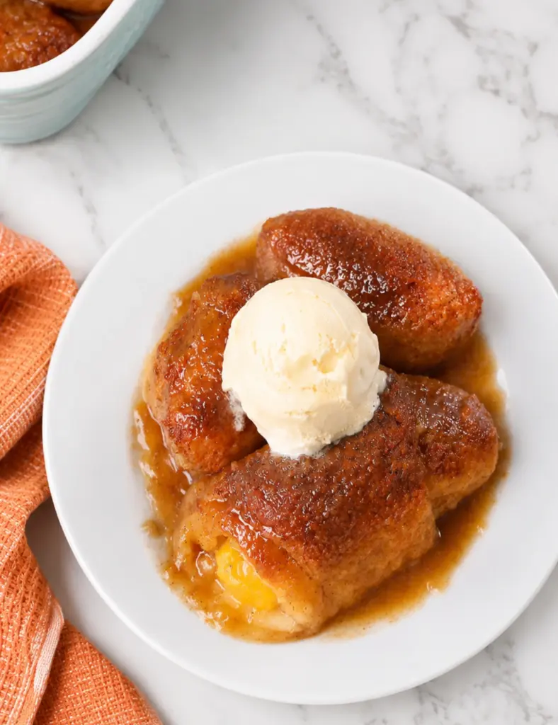 Peach Dumplings with Crescent Rolls served with vanilla ice cream on a white plate