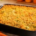 Freshly baked zucchini casserole with a crisp golden cheese topping in a black baking dish on a marble countertop.