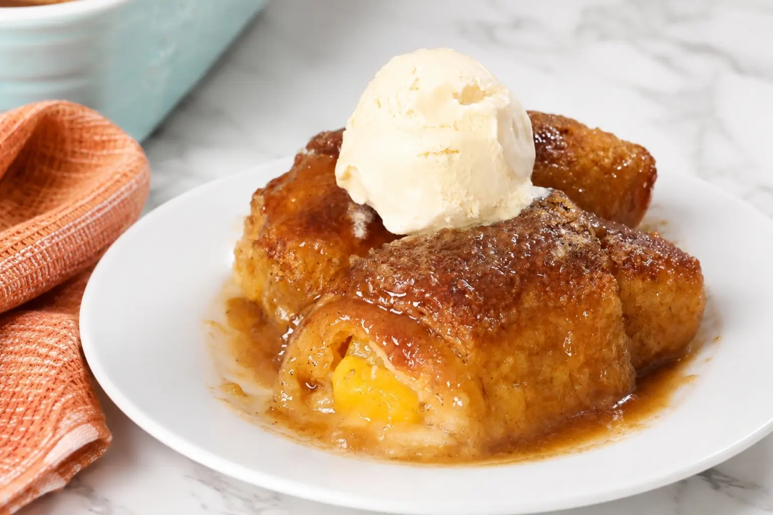 Peach Dumplings with Crescent Rolls topped with vanilla ice cream on a white plate